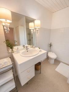 a white bathroom with a sink and a toilet at Maison Garesché - Chambres d'hôtes de charme avec table d'hôtes in Nieulle-sur-Seudre