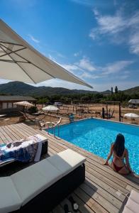 a woman sitting on a deck next to a swimming pool at Les Chalets de Tesa Adults Only in Occhiatana