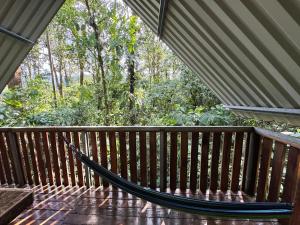 a hammock on a deck with trees in the background at Cabaña Escondida Rio Celeste in El pilon