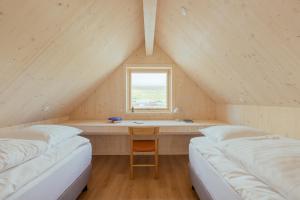 a room with two beds and a desk in a attic at The Lakehouse in Miðvágur