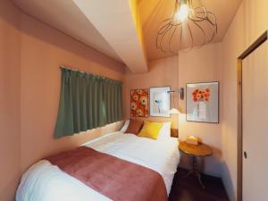 a small bedroom with a bed and a chandelier at Meijo Mikan Stay in Nagoya