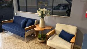 a couch and two chairs and a table with a vase of flowers at Ribs Hotel in Piauí
