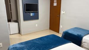 a room with two beds and a flat screen tv at Ribs Hotel in Piauí