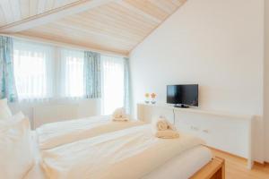 a white bedroom with a bed and a tv at Chalet SOLYMONT by MoniCare in Seefeld in Tirol