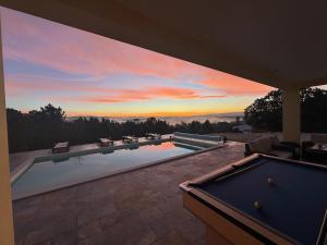 a swimming pool with a pool table in front of a sunset at Casa na Colina - Private Pool & Jacuzzi in Santiago da Guarda