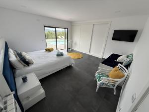 a bedroom with a bed and a chair in it at Casa na Colina - Private Pool & Jacuzzi in Santiago da Guarda