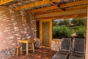 un patio con mesa y sillas en la pared en Eco-Lodge El Andinista en San Pedro de Atacama