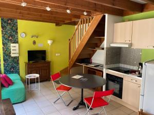 a kitchen and dining room with a table and red chairs at La Maisonnette in Les Andelys