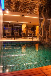 a swimming pool in a hotel with chairs and tables at Vila-L Hotel in Tirana