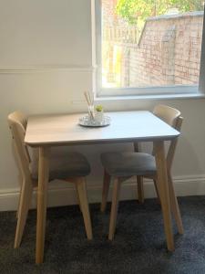 a wooden table with two chairs and a window at Premium Bedroom Escape in Hull