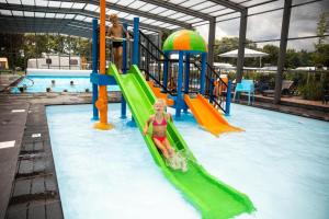 a young girl sliding down a slide in a swimming pool at Vakantiepark de Witte Berg in Ootmarsum