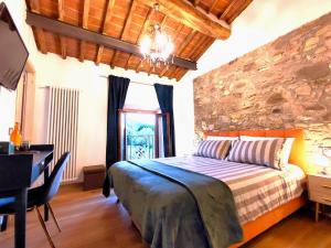a bedroom with a bed with a desk and a stone wall at B&B Toringo in Capannori