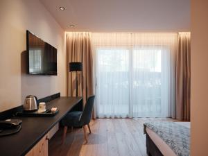 a hotel room with a bed and a desk and a window at Cityhotel Goldener Adler B&B in Chiusa