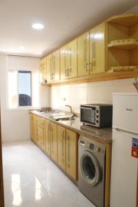 a kitchen with wooden cabinets and a washer and dryer at Apart al hoceima in Al Hoceïma