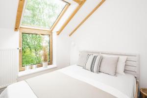 a white bedroom with a bed and two windows at Apartamenty Leszka 2, self check in 24h in Poznań