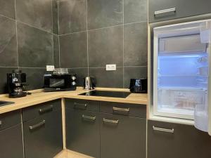 a kitchen with a sink and an open refrigerator at Ancram SPA Miskolc in Miskolc