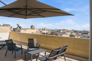 a patio with chairs and a table and an umbrella at Casa Lina Suites in Sliema
