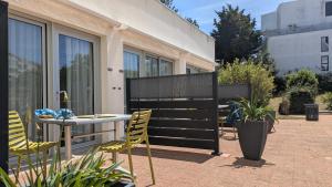 a patio with yellow chairs and a table and a building at Résidence avec Piscine face au port 200m plage in La Rochelle