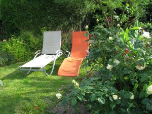 une chaise orange et blanche assise dans l'herbe dans l'établissement Gîte l'Hermine, à Val Couesnon