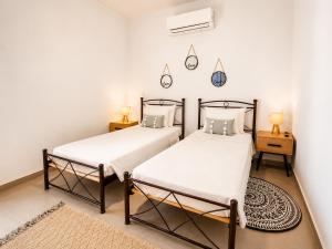 two twin beds in a room with white walls at Maquestas Modern Apartments in Archangelos +7 photos