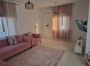 a living room with a pink couch and a rug at home byrsa in Douar ech Chott