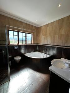 a bathroom with a tub and a toilet and a sink at Acacia House in Winterton +44 photos