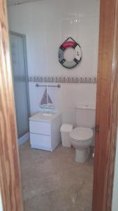 a bathroom with a toilet and a clock on the wall at Sunrise Hill Guest House in Los Gallardos +11 photos