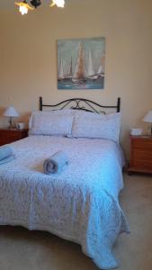 a bed with a blue comforter with two sailboats on it at Sunrise Hill Guest House in Los Gallardos