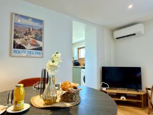 a living room with a table and a tv at Entre Terre et Vignes - Studio climatisé in Marlenheim