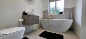 a bathroom with a tub and a toilet and a window at Stoney Lane Cottage in Wakefield