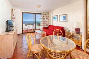a living room with a red couch and a table and chairs at Apartamentos Masaru in Puerto de la Cruz