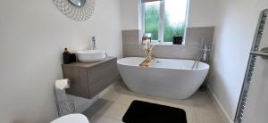 a white bathroom with a tub and a sink at Stoney Lane Cottage in Wakefield