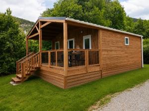 a large wooden cabin with a deck on the grass at Villages de Chalets et camping La Pierre de l'Aigle in La Bréole
