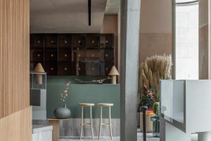 a kitchen with a green counter with stools and cabinets at Buckle Street Studios by Locke, Aldgate in London