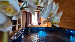a swimming pool with white flowers in a room at Hotel La Font Vineuse & Spa in Saint-Pierre-dʼArgençon