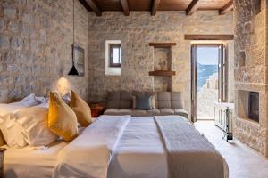 a bedroom with a large bed and a stone wall at Petra & Fos Boutique Hotel & Spa in Neo Itilo