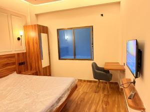 a bedroom with a bed and a desk and a television at Rishaan Regency in Silchar