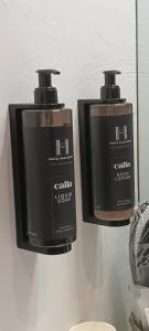two black soap dispensers hanging on a wall at Hotel Palladium in Monastir