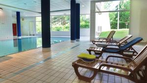 a pool room with chairs and a swimming pool at VVF Alsace Orbey Colmar in Orbey