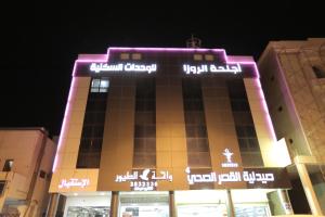 un edificio con luces moradas encima en Alrosa Furnished Apartments, en Buraidah