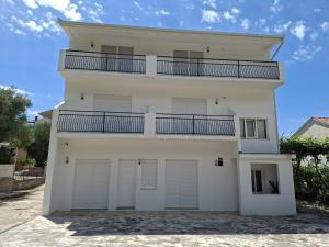 a white house with two garage doors and a balcony at Apartments Sunce in Podaca
