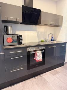 a kitchen with a stove and a microwave at Beautiful Apartment in Mönchengladbach mit Wintergarten in Mönchengladbach