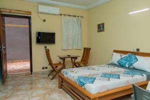 a bedroom with a bed and a table and a television at Résidence Royale Emma in Abidjan