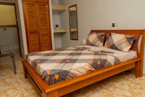 a bedroom with a bed with a wooden frame and pillows at Résidence Royale Emma in Abidjan