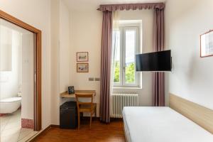 a bedroom with a bed and a desk and a window at Hotel Quarcino in Como