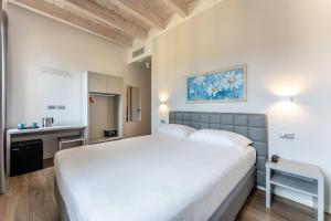 a bedroom with a large white bed and a kitchen at Hotel Quarcino in Como +38 photos