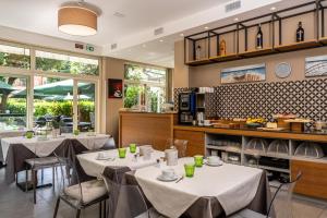 a restaurant with white tables and chairs and windows at Hotel Quarcino in Como