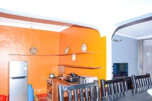 a kitchen with an orange wall with a refrigerator at Larry Homestay in Kapchorwa