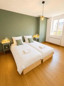 a bedroom with a large white bed with two pillows at Aux loges du théâtre in Moulins