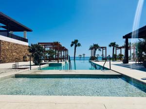 a large swimming pool with palm trees in the background at CocoBeach Mojácar - 3 min a pie de Playa Macenas in Mojácar